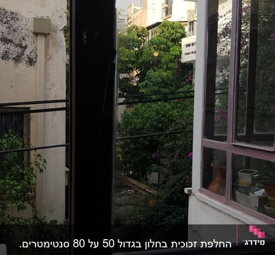 חלון זכוכית פתוח עם נוף חיצוני של בניינים ועצים